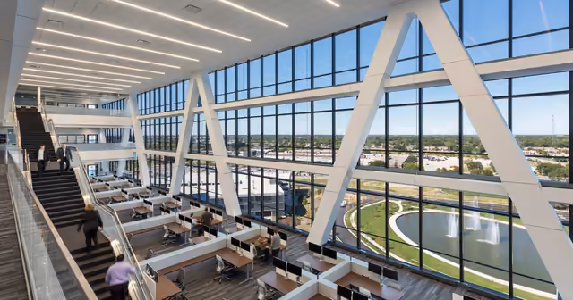 Inside Zurich North America's headquarters: a tall glass atrium over open workstations, a fountain pond outside