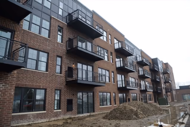 The Element apartment building near completion, brick and dark panels lined with balconies above a graded site