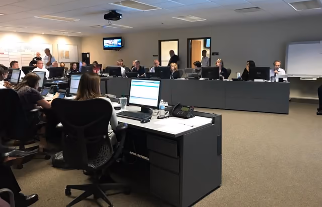 Staff at rows of computer desks in the Emergency Operations Center, screens on the far wall
