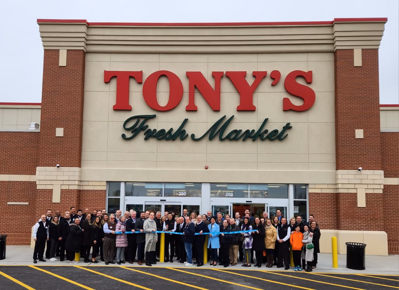 A crowd lined up for a ribbon cutting in front of the Tony's Fresh Market entrance