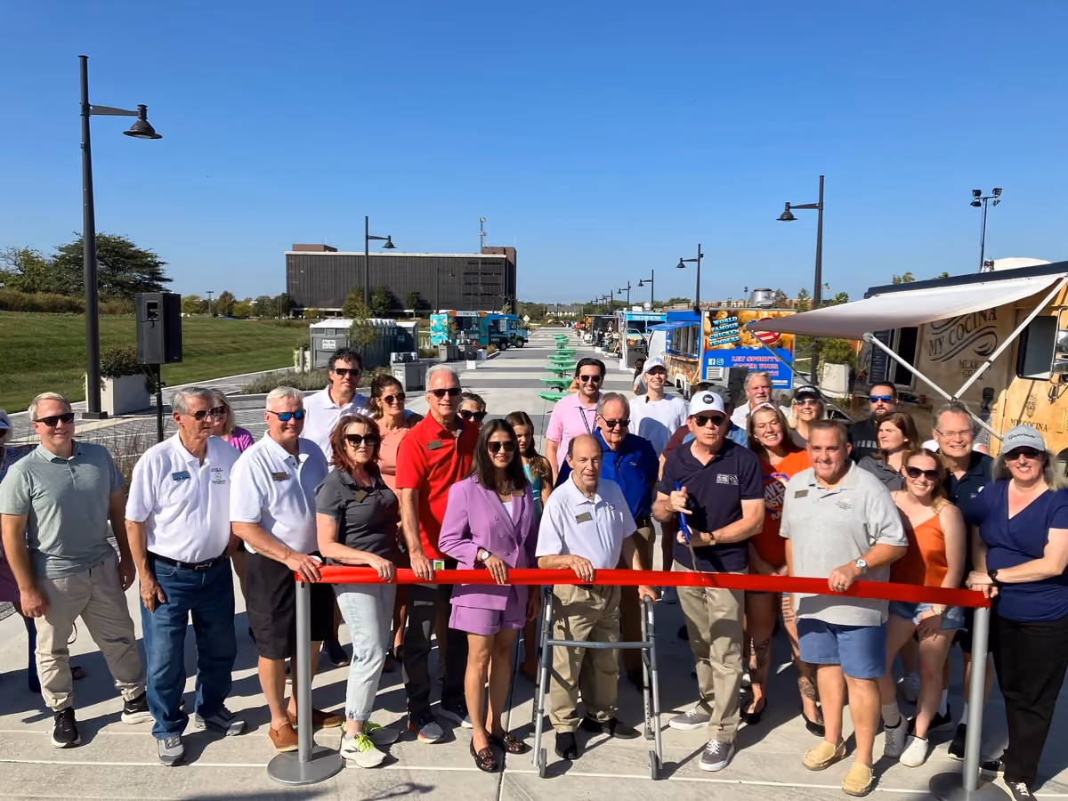 Village officials and guests cutting a red ribbon on Promenade Drive