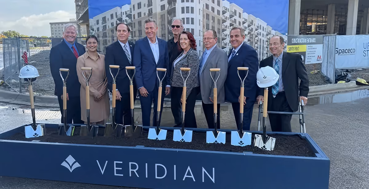 Officials holding ceremonial shovels behind a Veridian planter at the groundbreaking