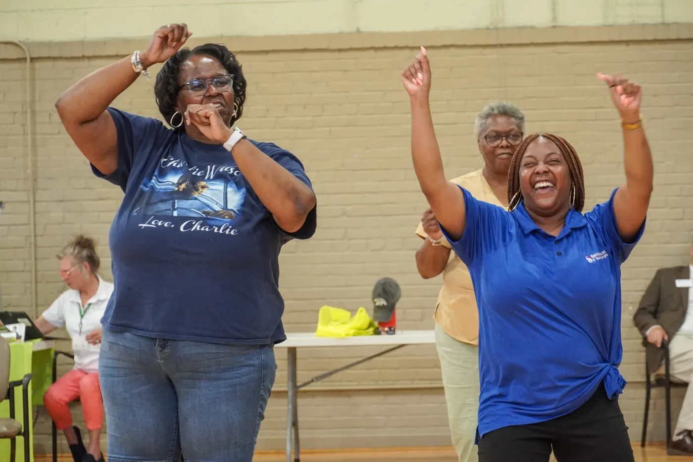 Three women dancing and cheering during an activity at a Senior Services program.