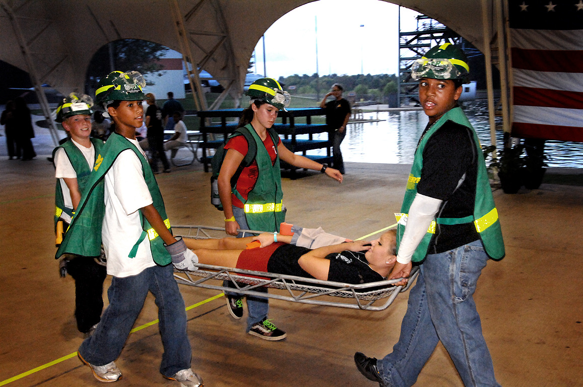 Young Alabama CERT volunteers carry a person on a stretcher during a community emergency-response training exercise.