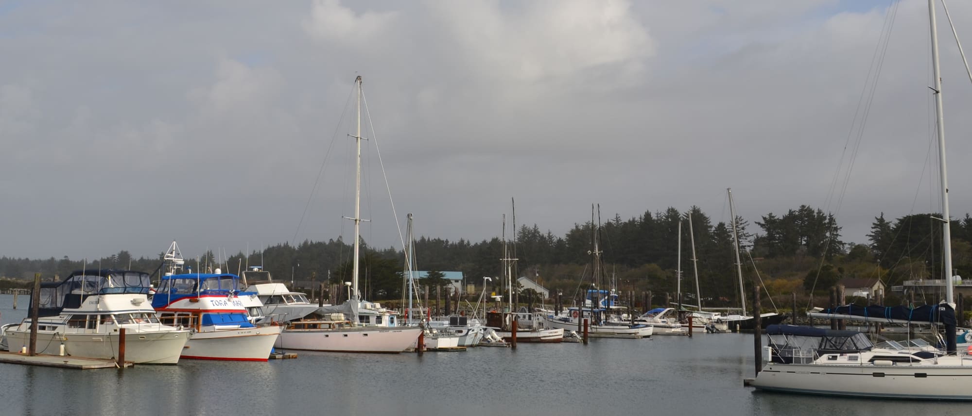 Fishing boats tied up along the docks at the Port of Bandon under a broken coastal sky.