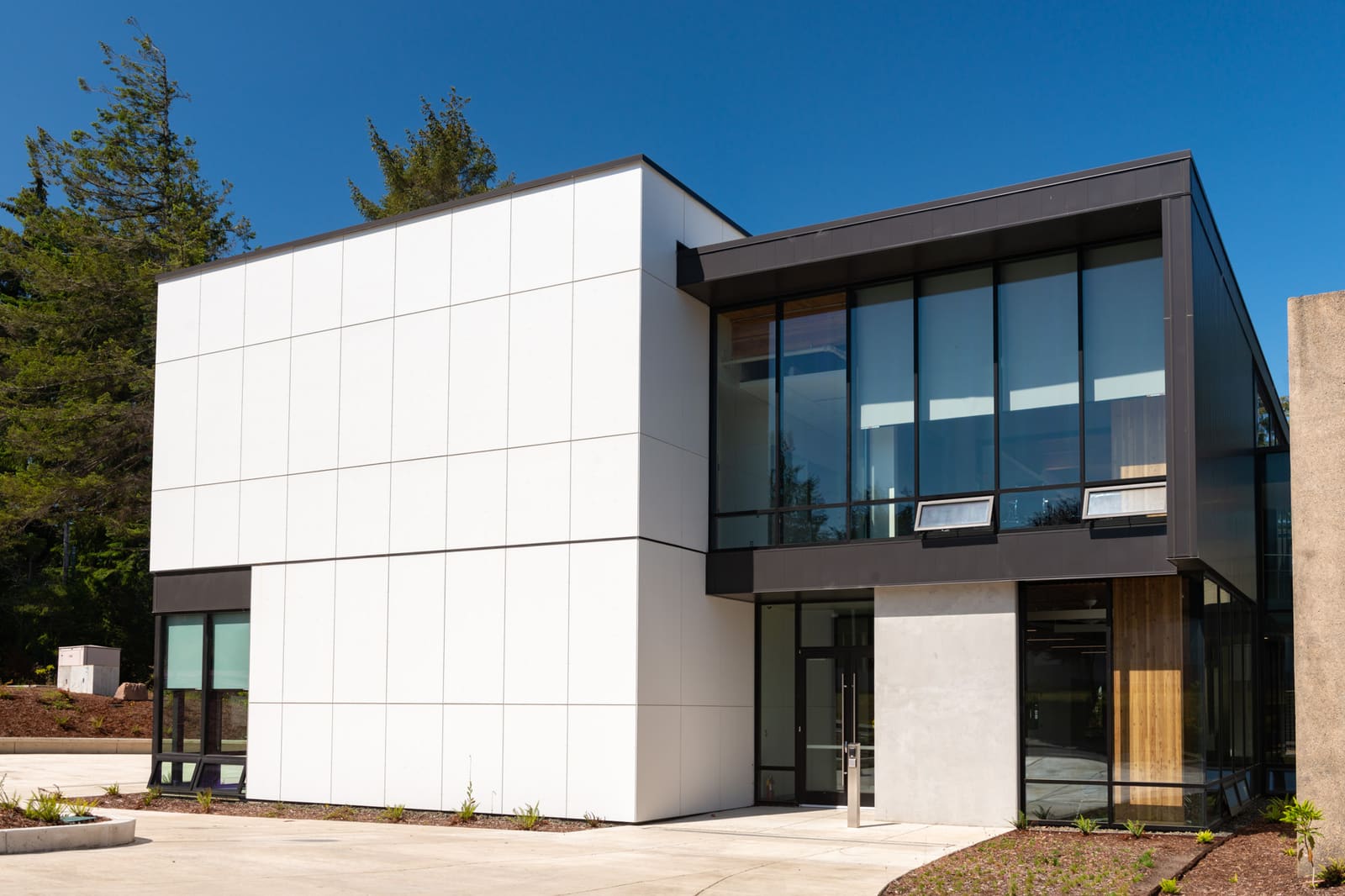 A white-panelled classroom building at Southwestern Oregon Community College in Coos Bay, its glazed corner and recessed entrance facing the camera.