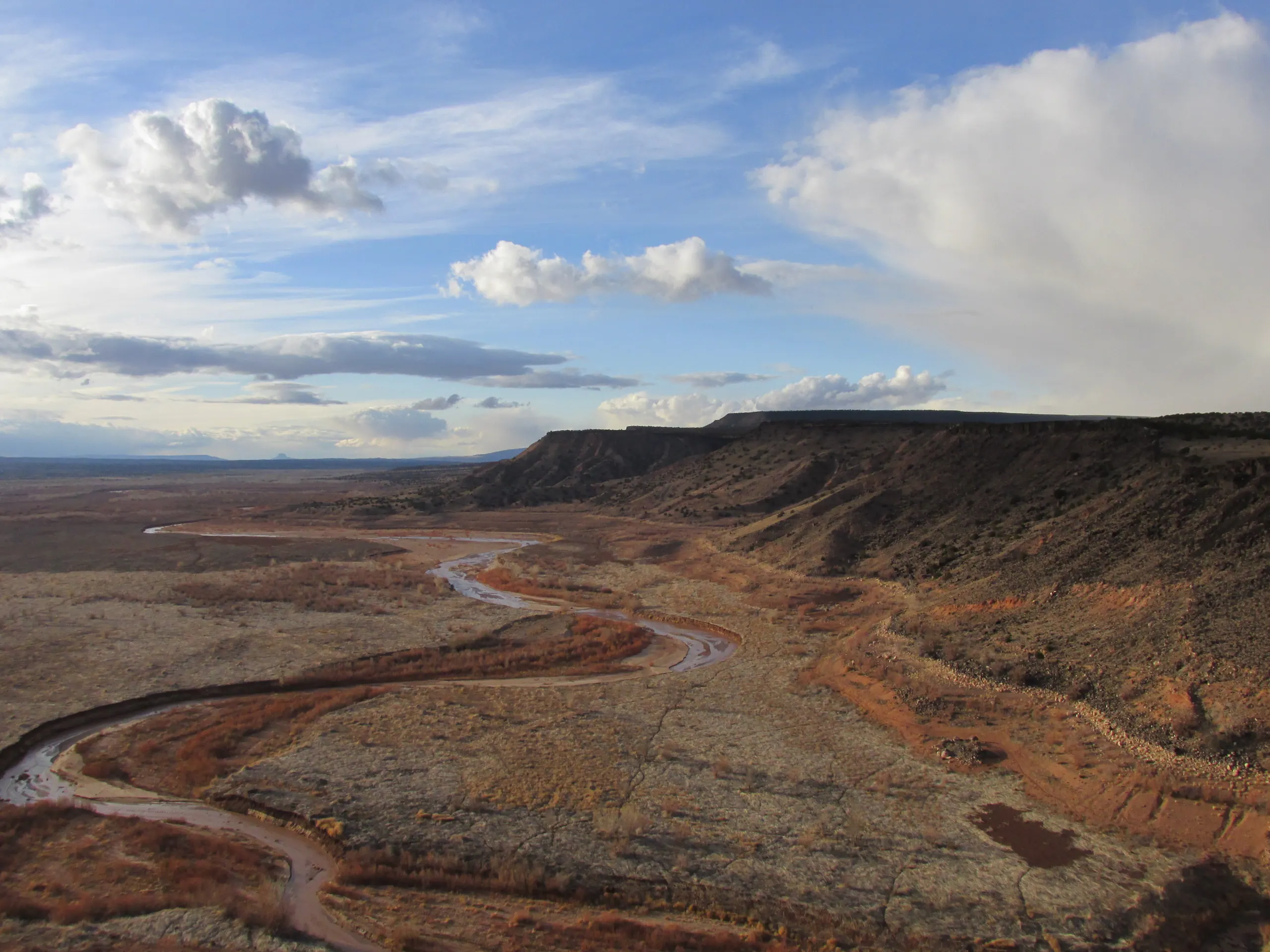 The Jemez River winding through red earth below a mesa at Santa Ana Pueblo.