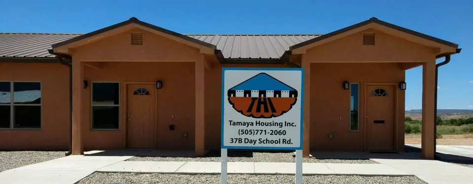 The Tamaya Housing office, a stucco building with a metal roof, with the THI sign out front listing 37B Day School Rd.