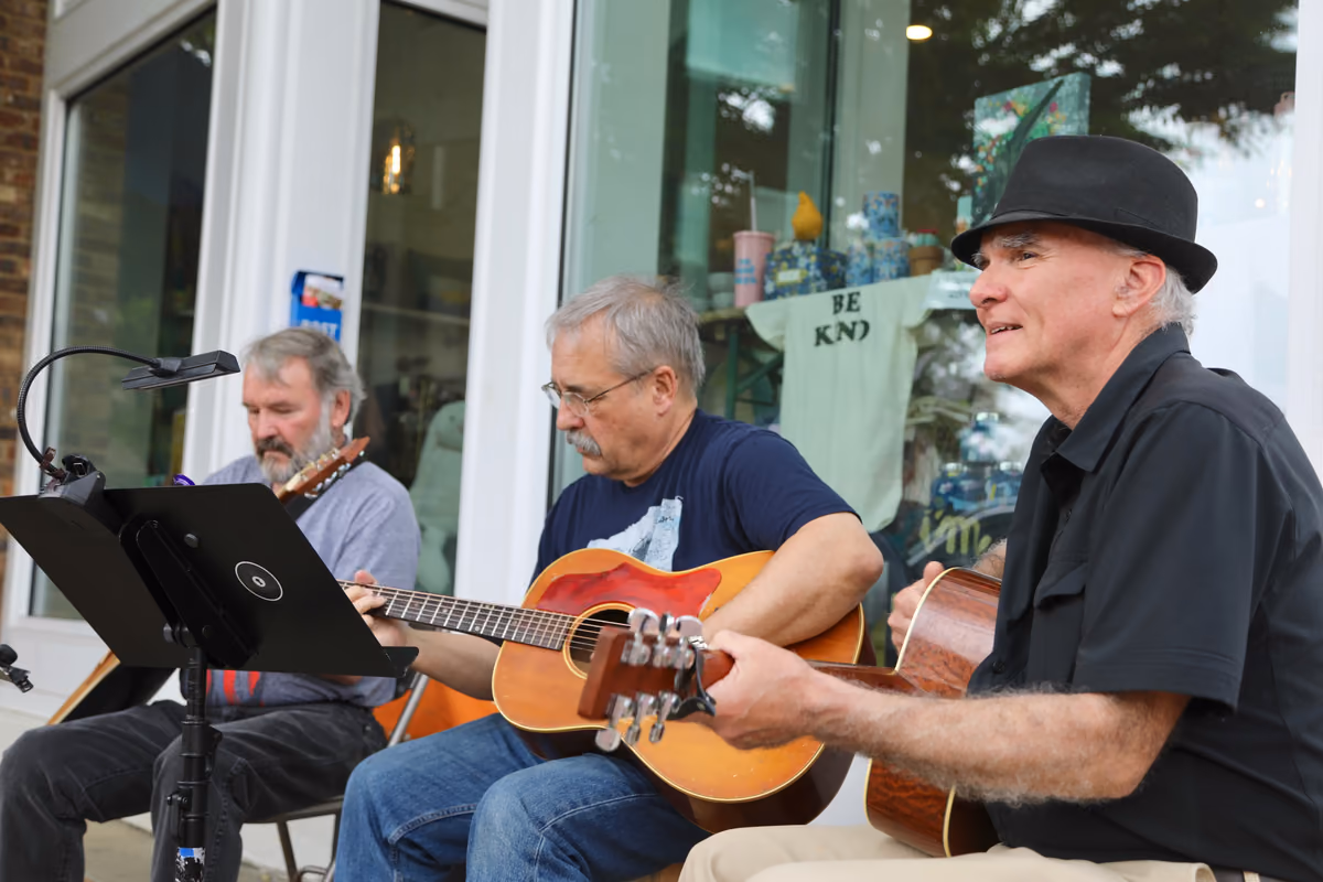 Three guitarists playing outside a shop on the Square at First Fridays.