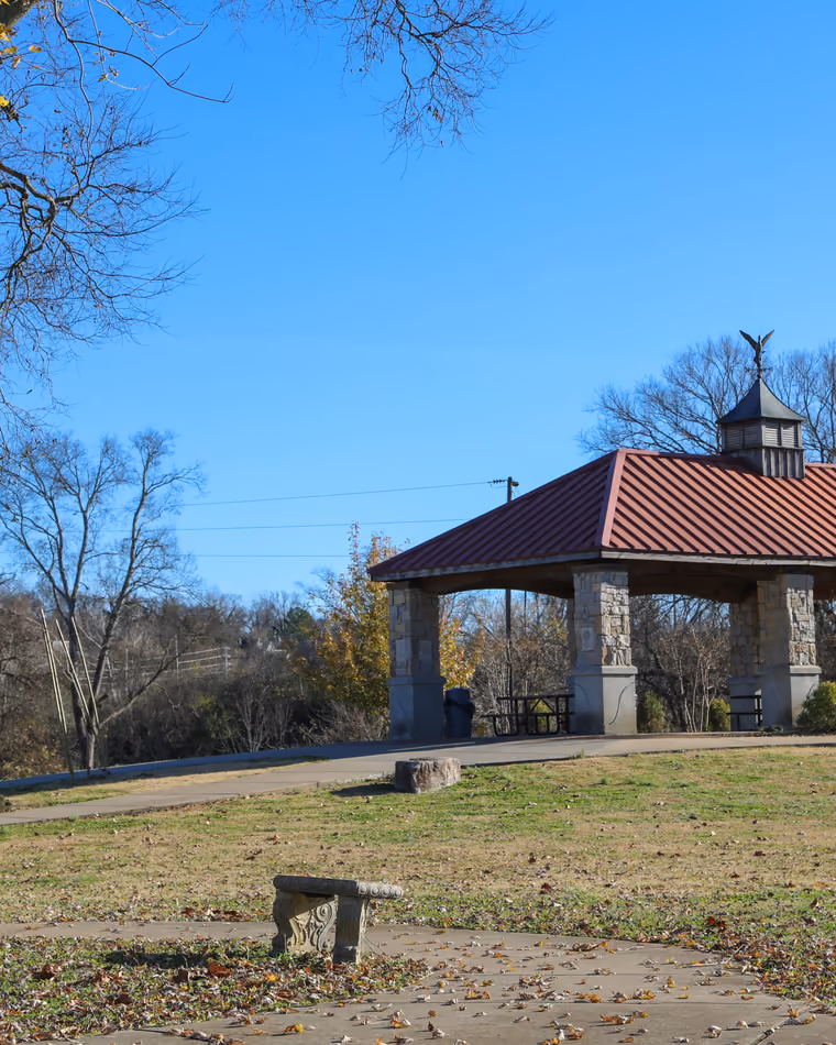 The stone and timber pavilion at Riverwalk Park under bare winter trees.