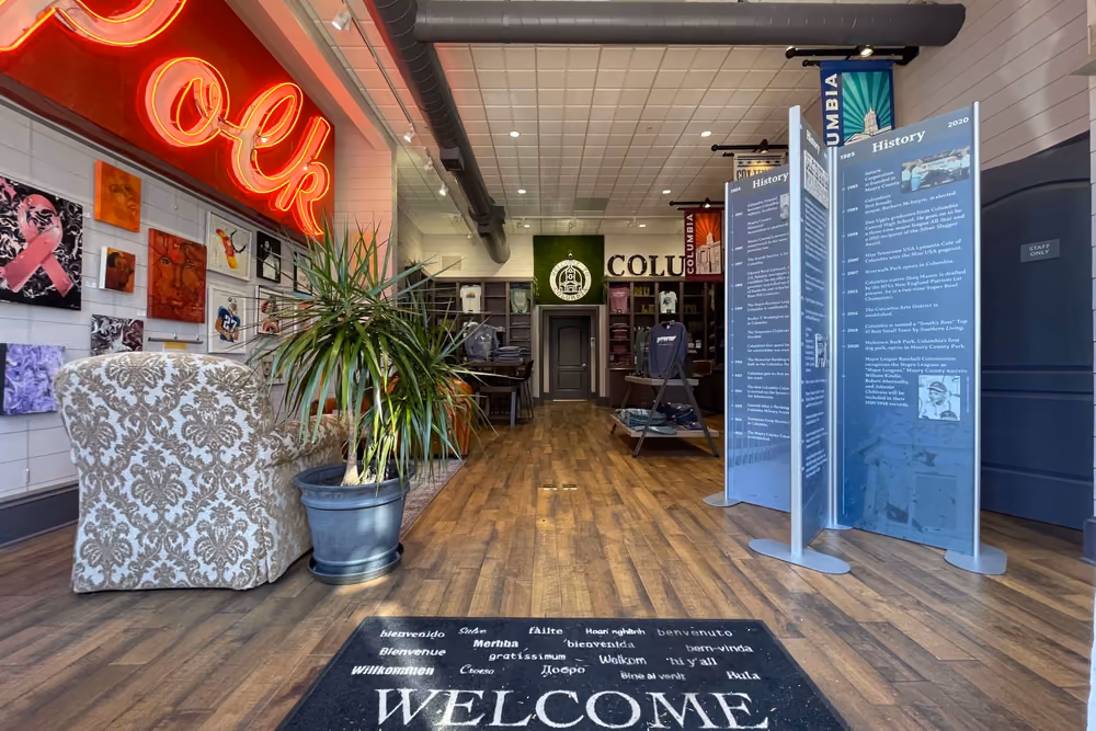 Inside the Columbia Welcome Center, with the red Polk neon sign above the entrance and exhibit panels along the wall.