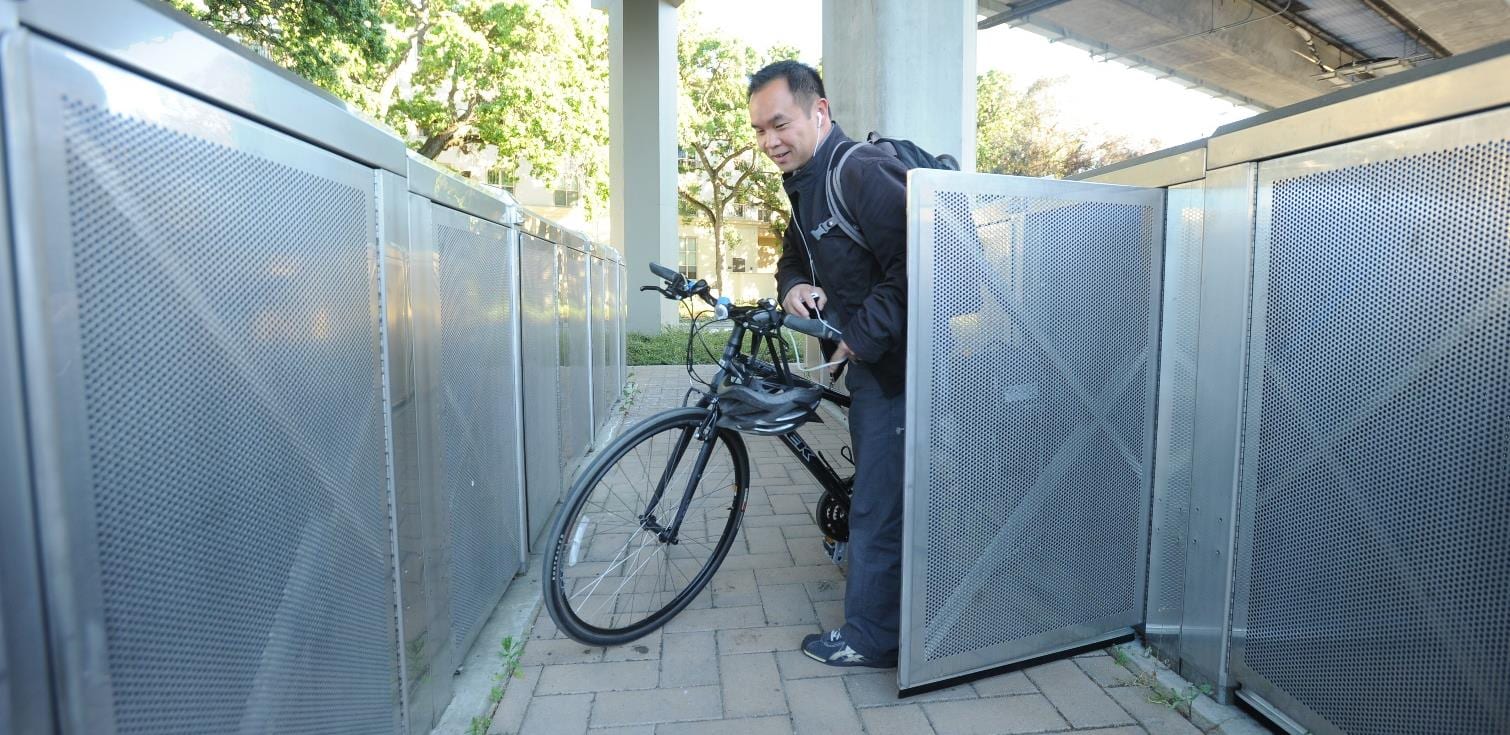A rider placing a bicycle in a secure locker at a West County station