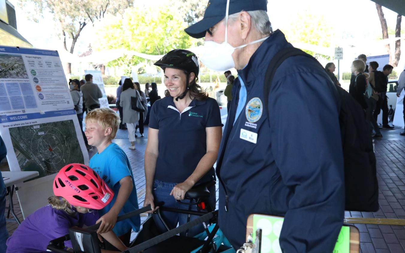 Children with bicycle helmets and adults at a West County transportation event