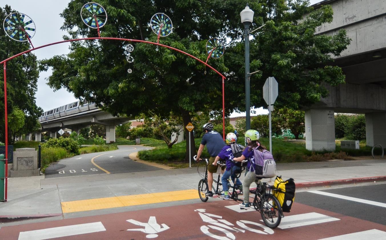 A family on a cargo bike crossing under the BART tracks at the Richmond Greenway