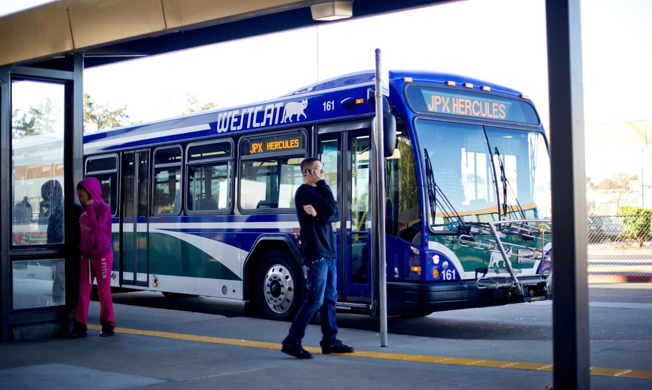 A WestCAT bus bound for Hercules and two riders at a West County transit center