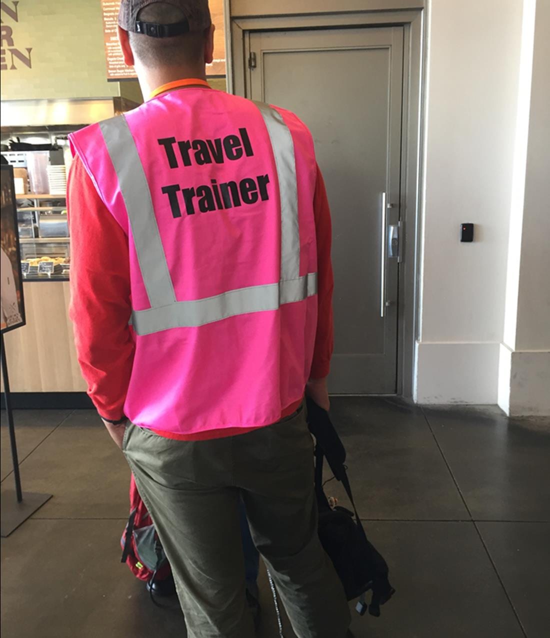 A WCCTC travel trainer in a pink safety vest escorting a rider through a station