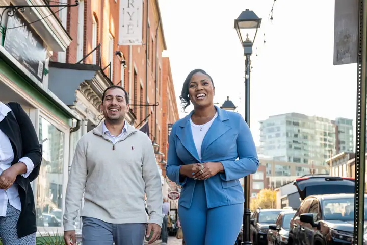Three Baltimore Weaver Awardees laugh as they walk together down a brick-lined city street.