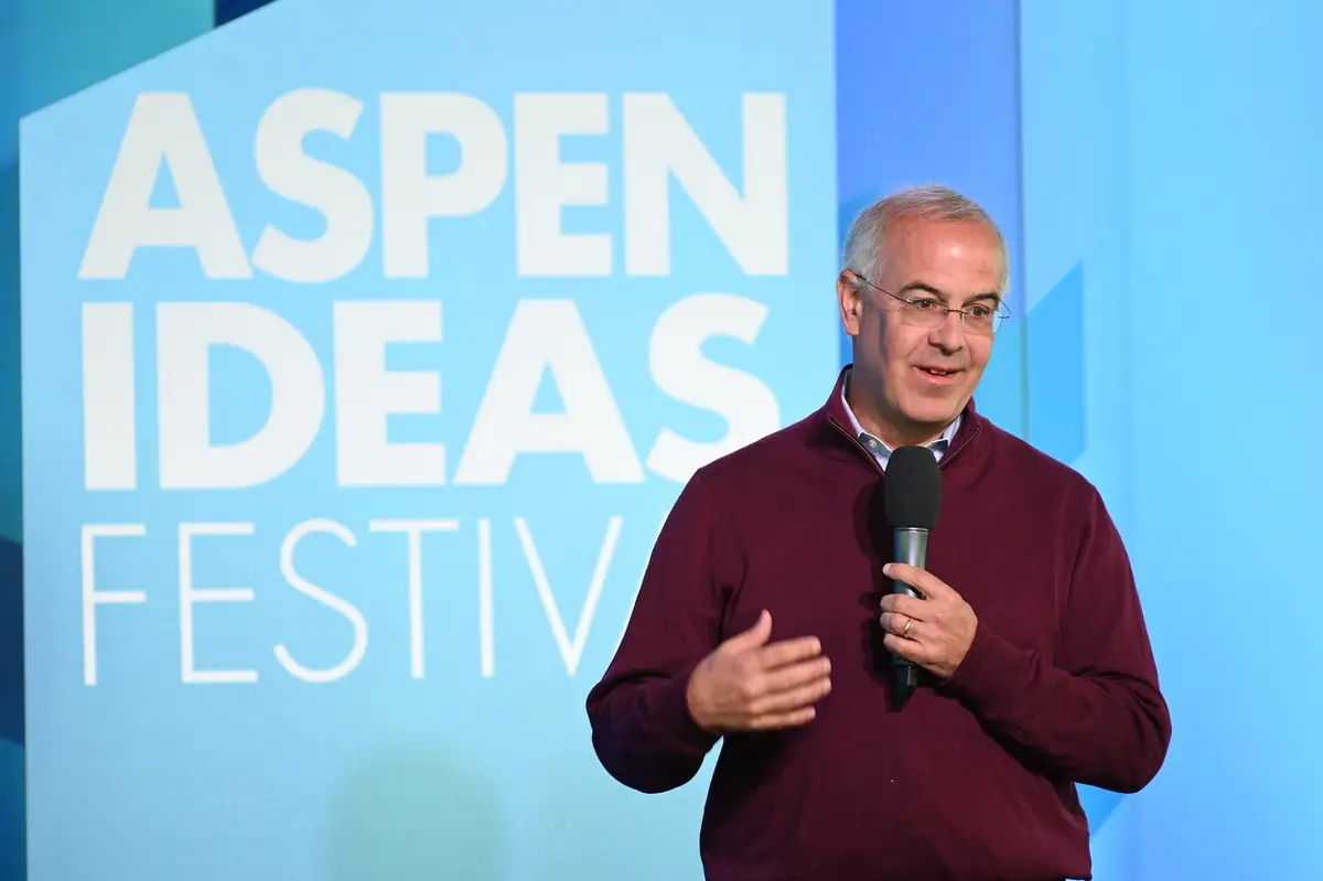 David Brooks speaks into a microphone in front of an Aspen Ideas Festival backdrop.