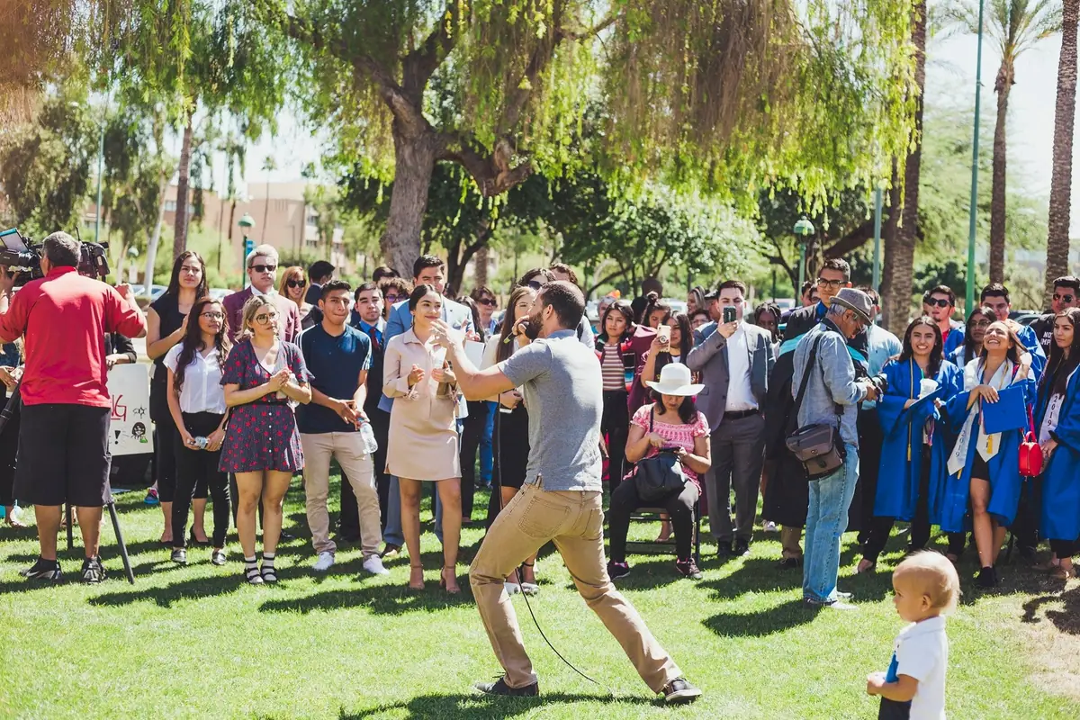 A performer dances in front of a large crowd on a lawn.