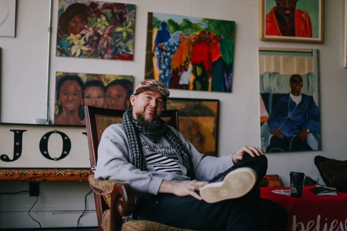 Elias Moreno Lothe sits back in an armchair below a wall of painted portraits.