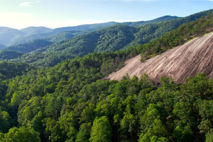 Forested mountains of the Appalachian foothills, with a bare granite dome rising out of the trees.