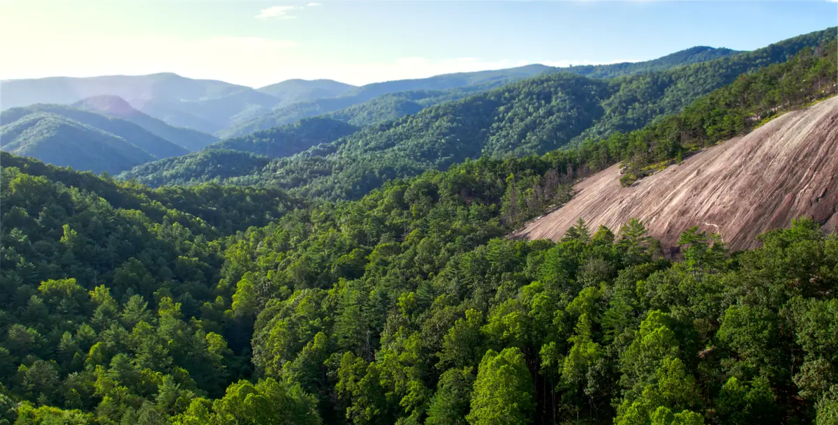 Forested mountains of the Appalachian foothills, with a bare granite dome rising out of the trees.