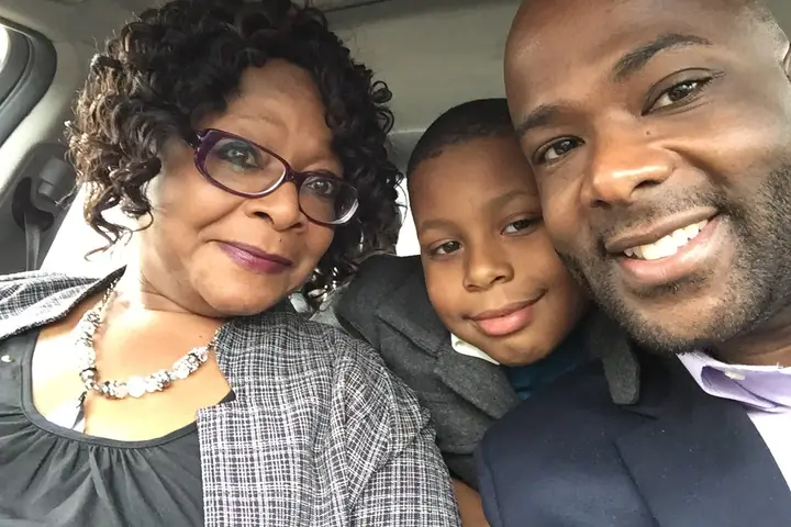 Frederick Riley, his mother and his young nephew smile together for a photo in a car.