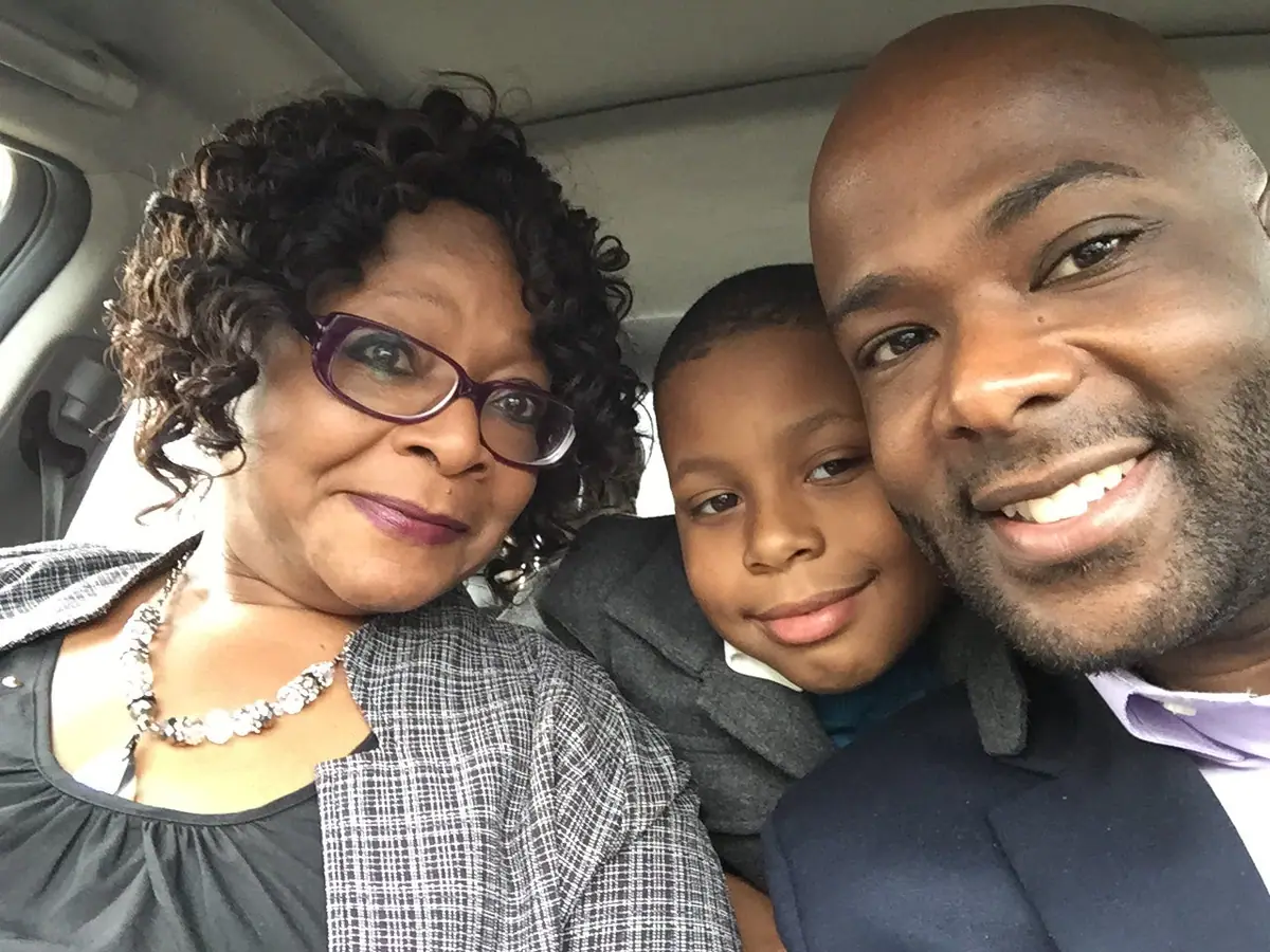 Frederick Riley, his mother and his young nephew smile together for a photo in a car.