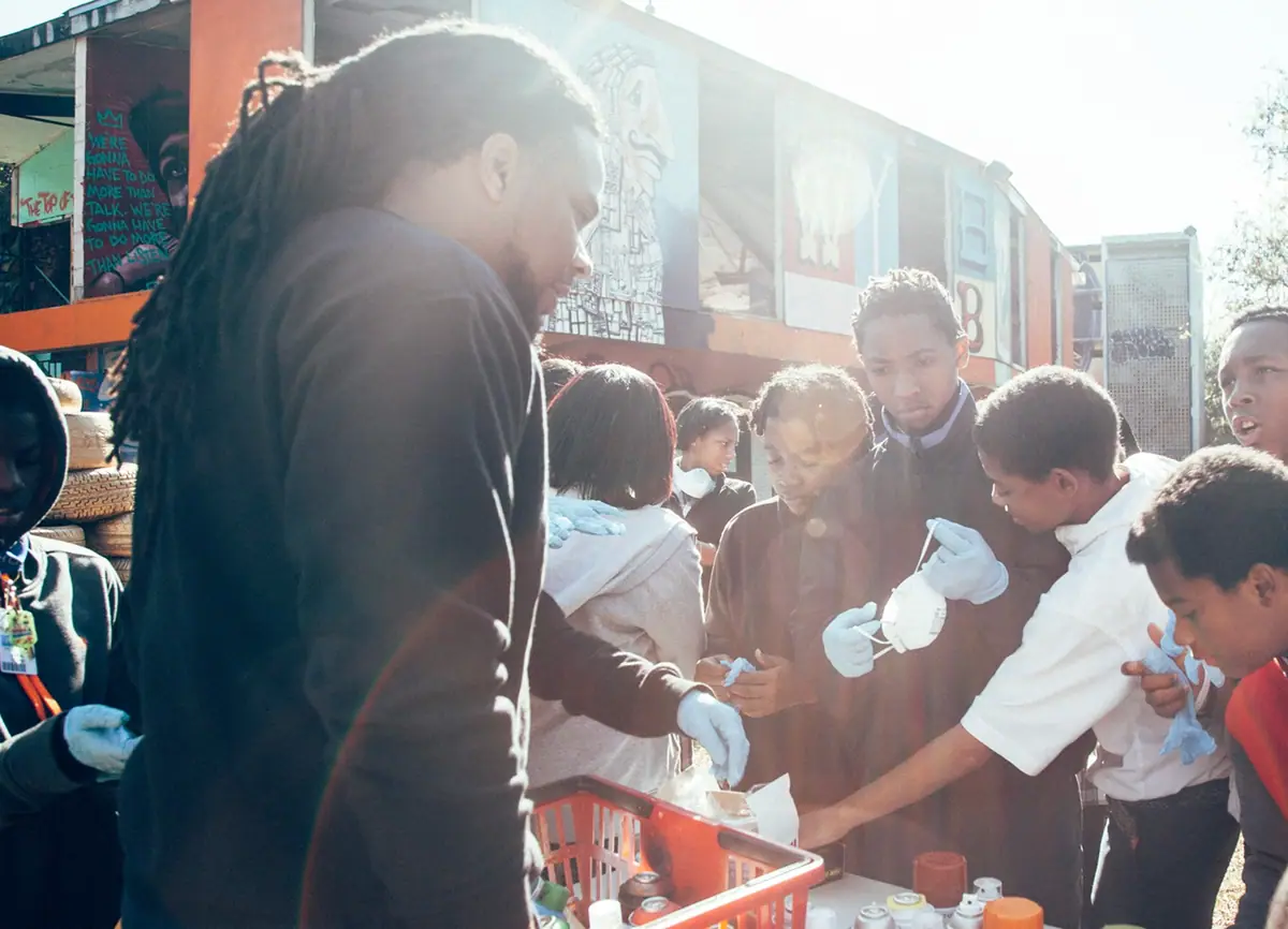A man hands out food to a crowd of children gathered outside a food truck.