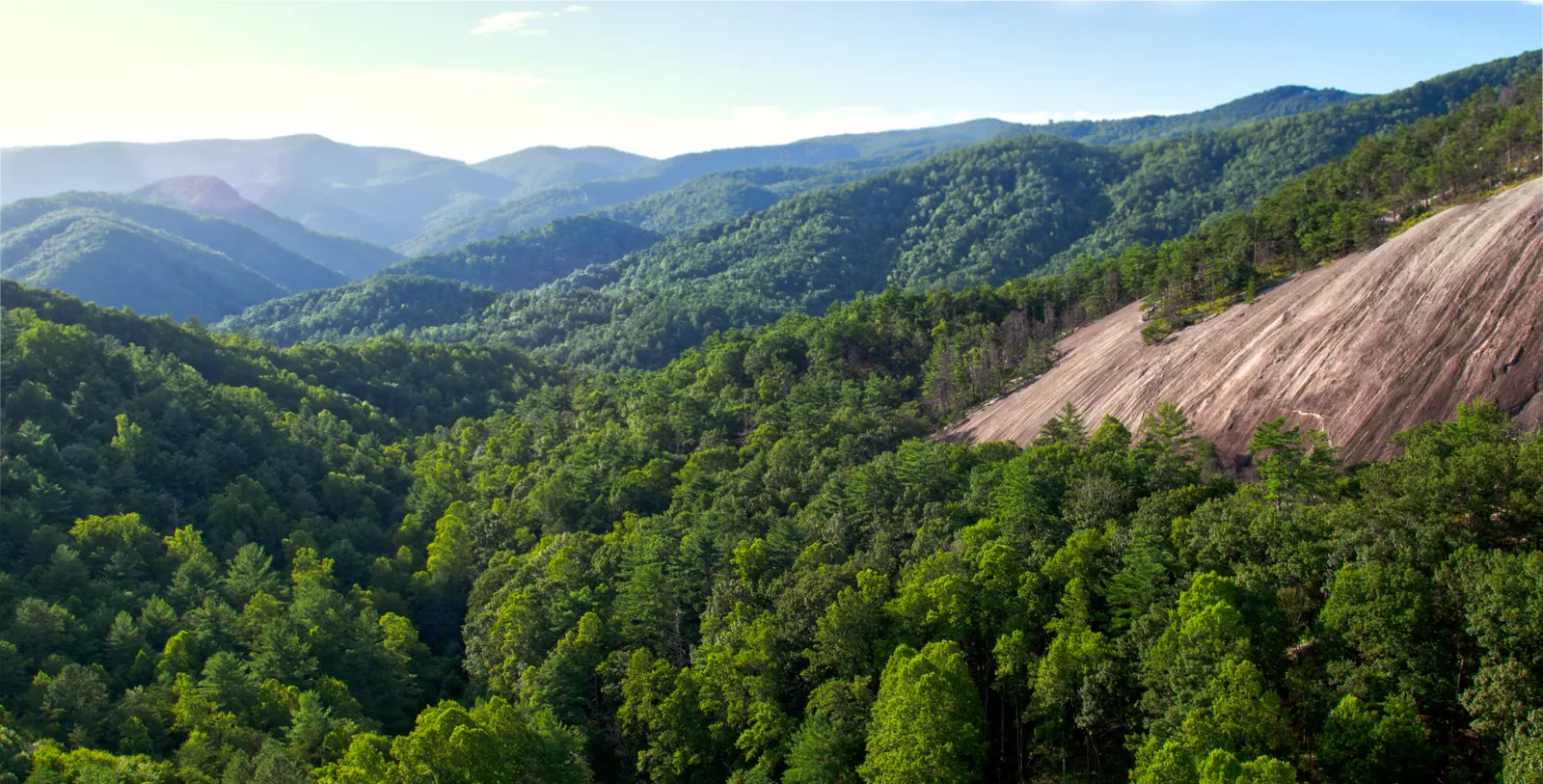 Forested mountains of the Appalachian foothills, with a bare granite dome rising out of the trees.