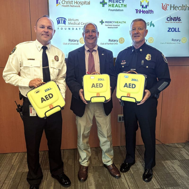 Jason Witte holds a donated AED with Police Chief Brian Rebholz and Assistant Police Chief Bruce Hoffbauer.