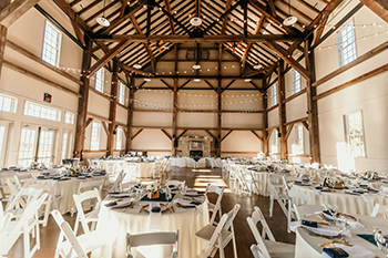 The timber-frame hall set with round tables for a reception.