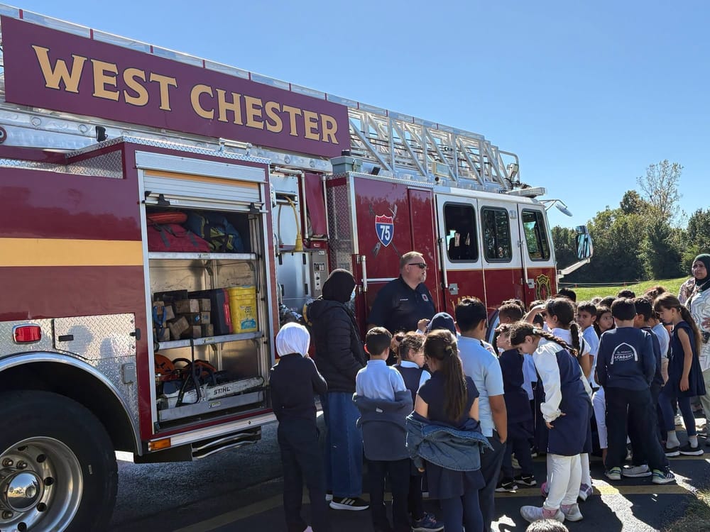 Schoolchildren gather around a West Chester fire engine during a station visit.