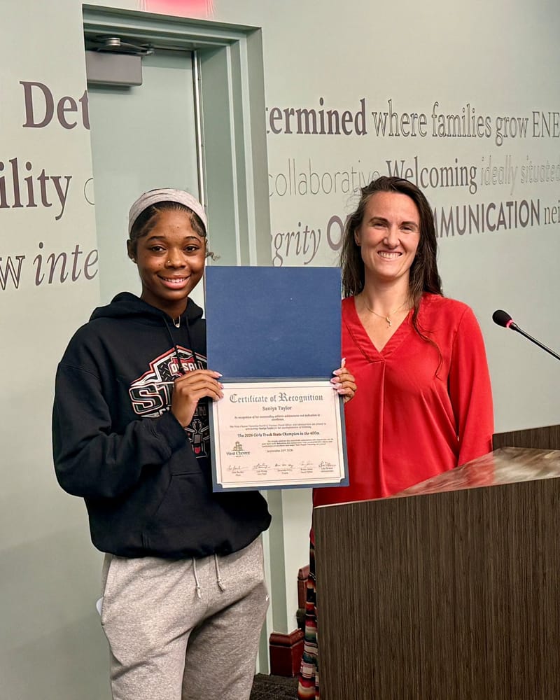 Saniya Taylor holds her Certificate of Recognition beside Public Information and Engagement Director Brianna Wooten at a Board of Trustees meeting.