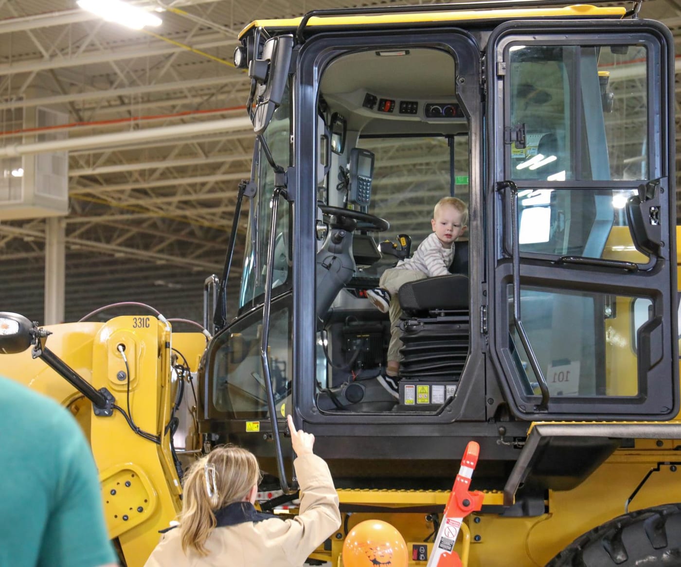 A little boy climbs in a skid loader as his Mom stands back to take the photos.